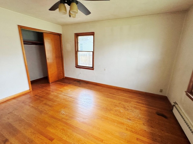 321 1st St, Bradford, IL 61421 - unfurnished bedroom featuring baseboard heating, light wood finished floors, a closet, and ceiling fan