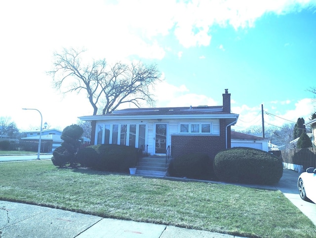 8550 S Avalon Ave, Chicago, IL 60619 - view of front facade with a chimney, a front yard, and brick siding