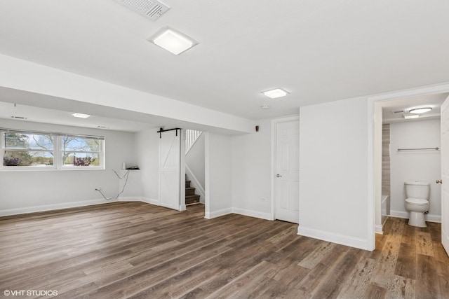 below grade area with stairs, baseboards, visible vents, and wood finished floors