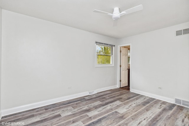 unfurnished room featuring baseboards, wood finished floors, and visible vents