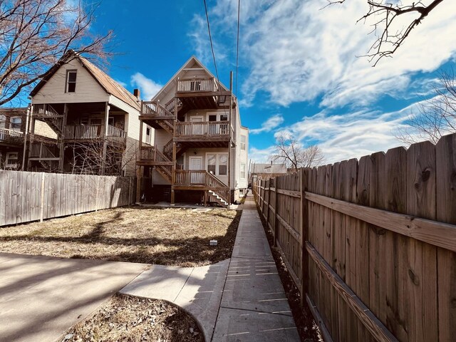 back of property with a balcony and a fenced backyard