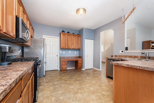 kitchen with stainless steel appliances, a sink, baseboards, built in desk, and brown cabinets