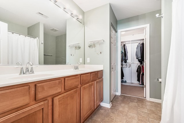 bathroom featuring baseboards, a sink, visible vents, and double vanity