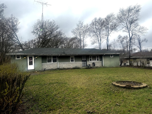rear view of house featuring a lawn, stone siding, and concrete block siding