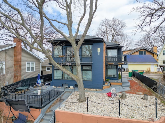 rear view of property with a balcony and fence