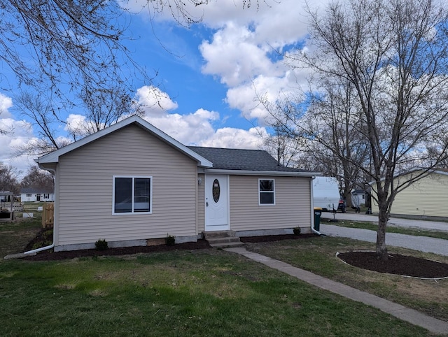 view of front of house with a front yard, a shingled roof, and entry steps