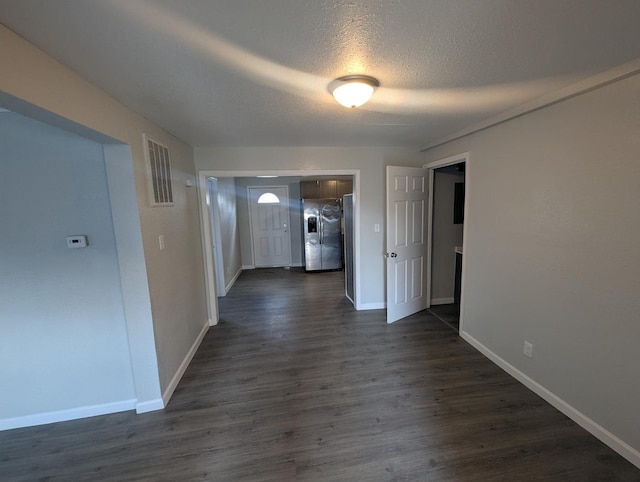 corridor featuring dark wood finished floors, a textured ceiling, baseboards, and visible vents