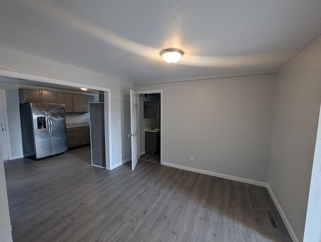 interior space with baseboards, visible vents, a textured ceiling, and dark wood-style flooring