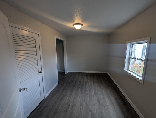 unfurnished bedroom featuring dark wood finished floors, baseboards, and a textured ceiling