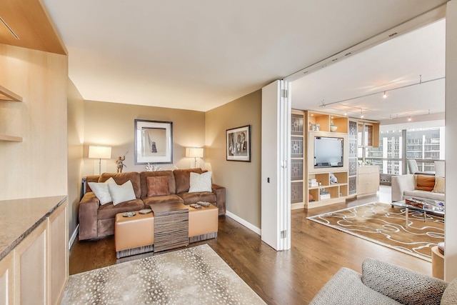 living area with track lighting, dark wood-style floors, and baseboards