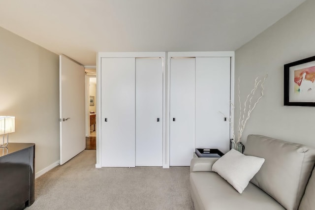 living area featuring light carpet and baseboards
