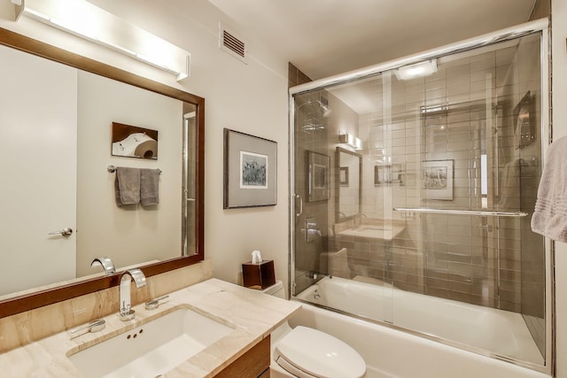 full bath with toilet, bath / shower combo with glass door, and vanity
