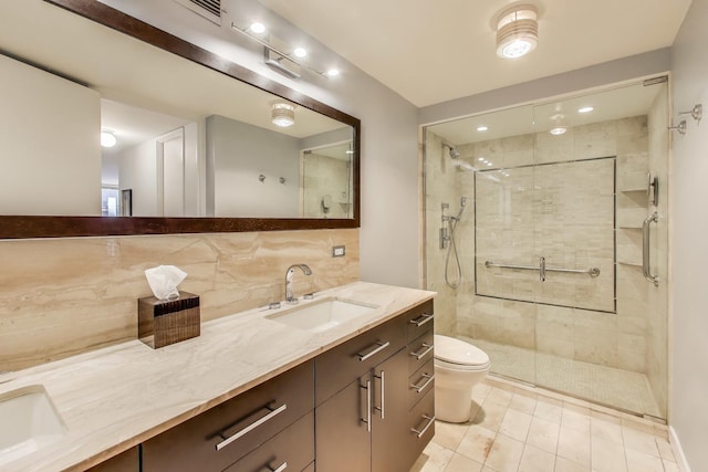 full bathroom featuring a stall shower, decorative backsplash, toilet, double vanity, and tile patterned floors