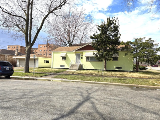 view of front of property featuring a front yard, entry steps, and a garage