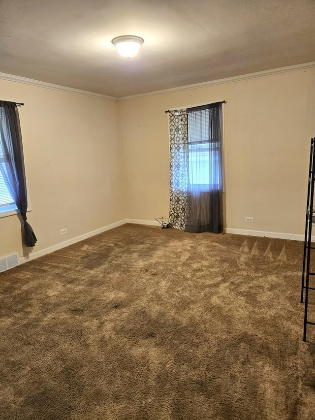 carpeted empty room featuring baseboards, ornamental molding, visible vents, and a wealth of natural light