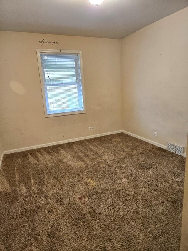 carpeted spare room with visible vents and baseboards