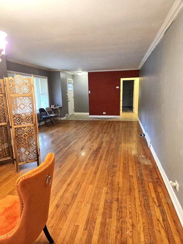 unfurnished living room with wood-type flooring, baseboards, and ornamental molding