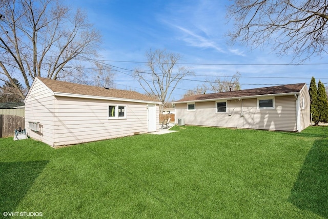 back of house with an outdoor structure, fence, and a lawn