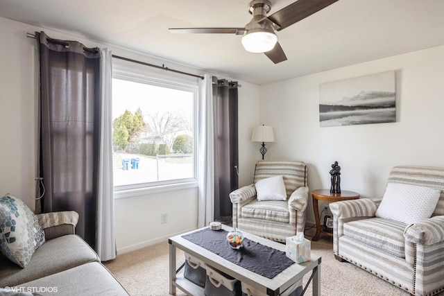 living area featuring light carpet, baseboards, and ceiling fan