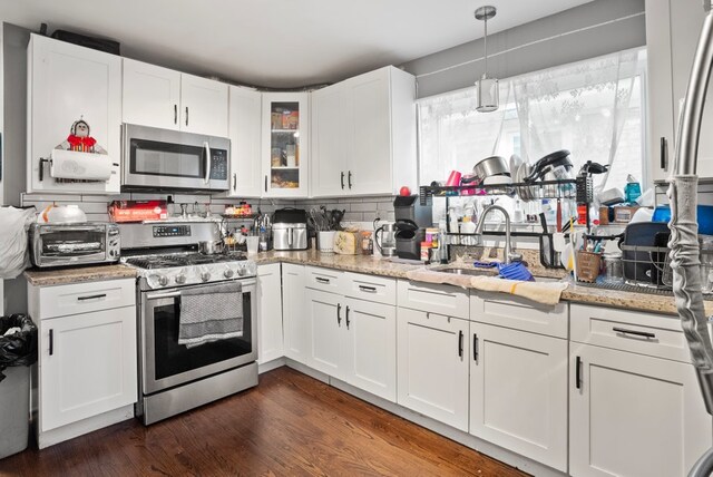 kitchen featuring decorative backsplash, a toaster, stainless steel appliances, a sink, and white cabinetry