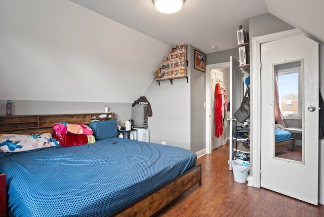 bedroom featuring wood finished floors, vaulted ceiling, and baseboards