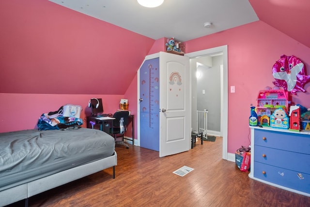 bedroom featuring baseboards, visible vents, wood finished floors, and vaulted ceiling