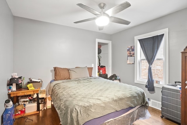 bedroom featuring wood finished floors, visible vents, a ceiling fan, and baseboards