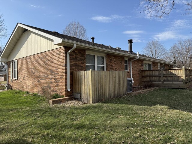 view of home's exterior featuring a deck, fence, a yard, and brick siding