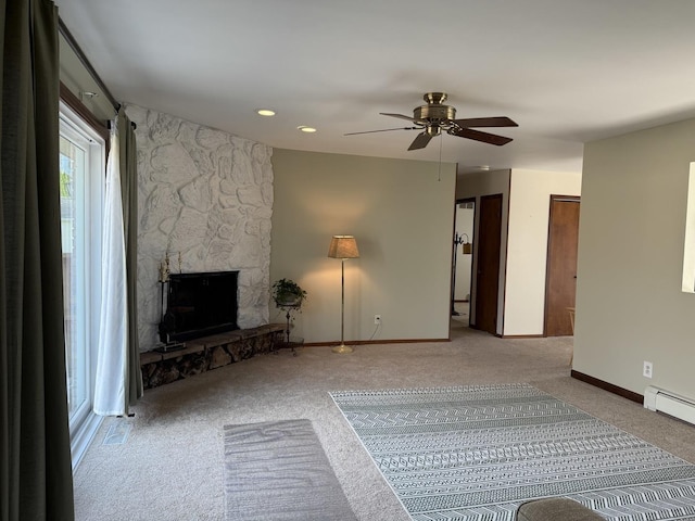 unfurnished living room featuring a stone fireplace, carpet flooring, ceiling fan, and baseboards