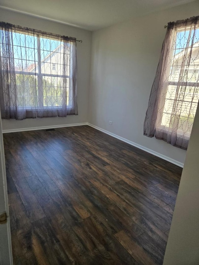 spare room with dark wood-type flooring, a wealth of natural light, a ceiling fan, and baseboards