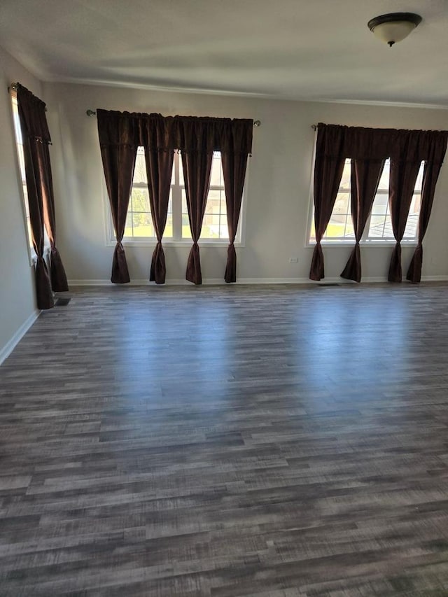 empty room with dark wood-style flooring and baseboards