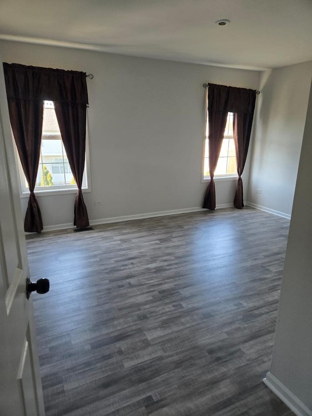 spare room with dark wood-style flooring and baseboards