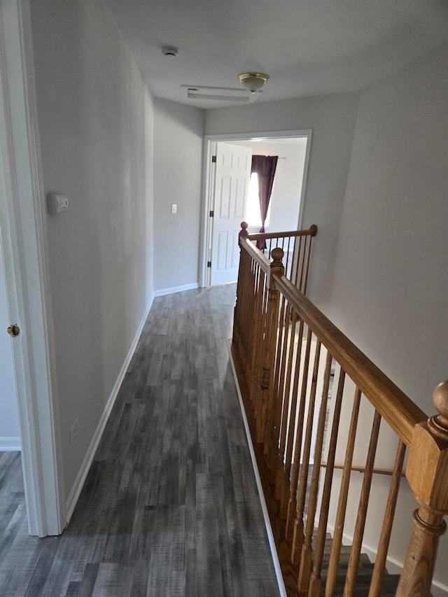 hallway with dark wood-type flooring, an upstairs landing, and baseboards