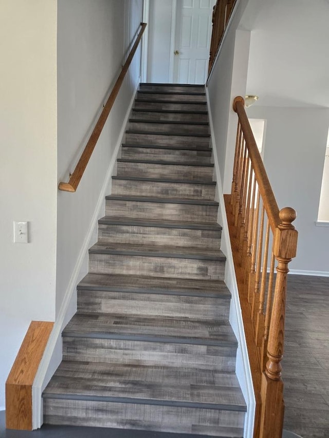 staircase featuring wood finished floors and baseboards
