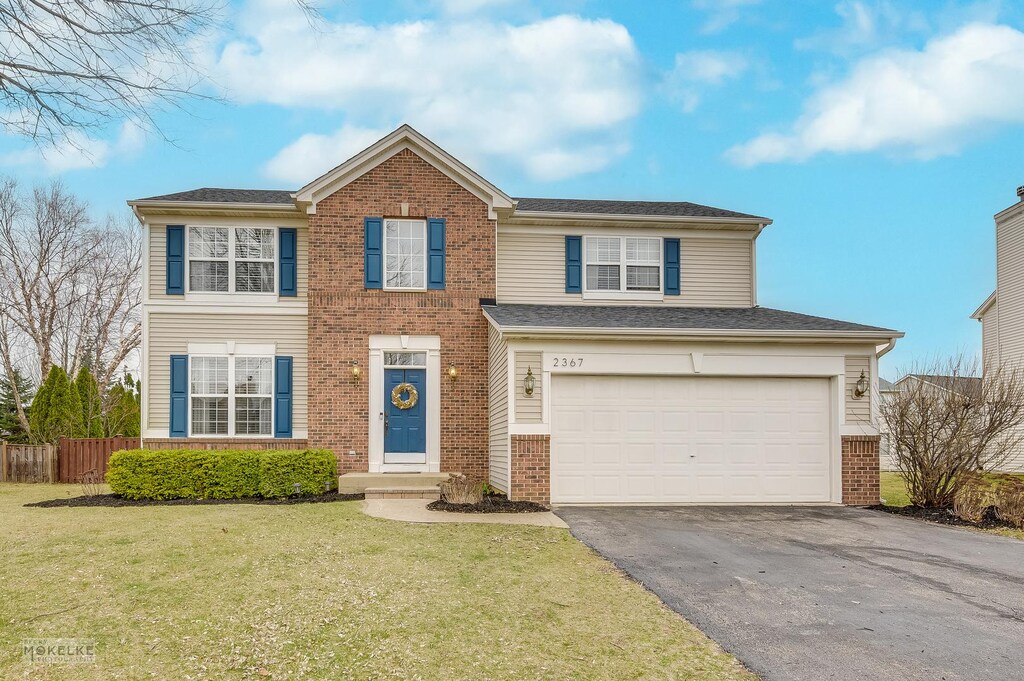 2367 Wilson Creek Cir, Aurora, IL 60503 - view of front of property with fence, driveway, a front yard, brick siding, and a garage