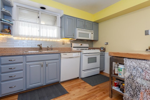 kitchen with white appliances, gray cabinets, decorative backsplash, a sink, and light wood finished floors