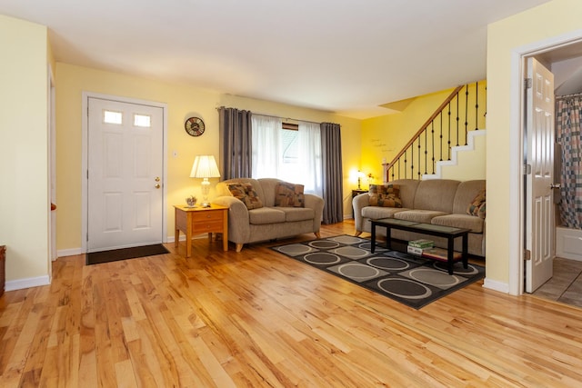 living room with baseboards, stairs, and light wood-type flooring