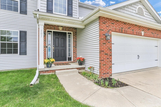 view of exterior entry with a garage, brick siding, and concrete driveway