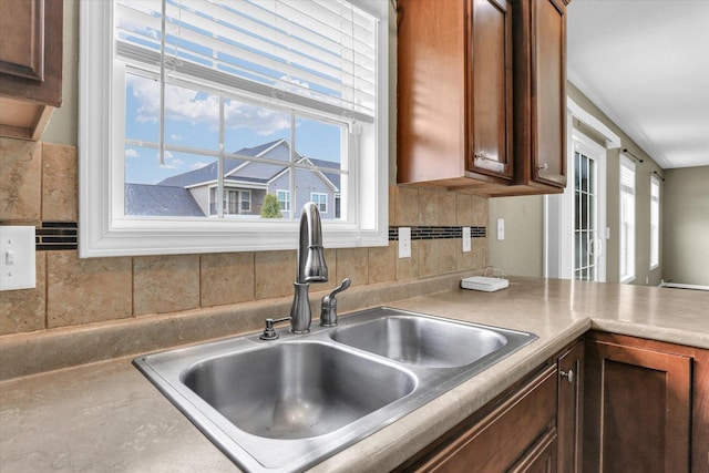 kitchen with a sink, backsplash, and light countertops