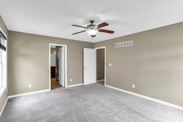 unfurnished bedroom with carpet flooring, baseboards, connected bathroom, and ceiling fan
