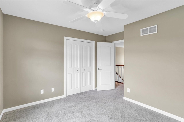 unfurnished bedroom with carpet flooring, baseboards, a closet, and a ceiling fan