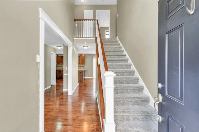 foyer entrance with wood finished floors, stairs, and baseboards