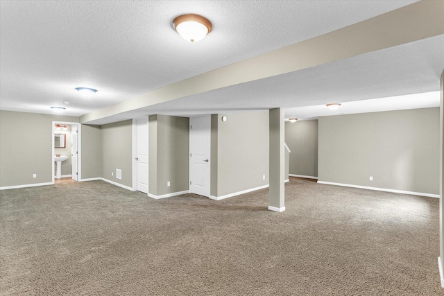 finished below grade area with carpet floors, baseboards, and a textured ceiling