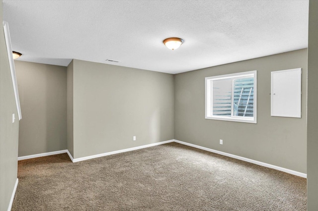 carpeted spare room featuring baseboards and a textured ceiling