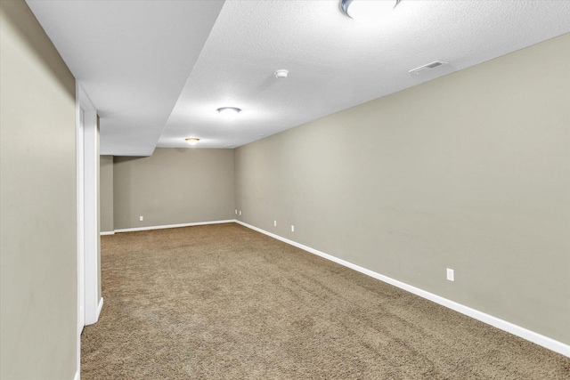 finished basement featuring carpet floors, baseboards, and a textured ceiling