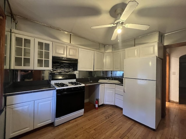 kitchen with dark countertops, gas stove, white cabinetry, ventilation hood, and freestanding refrigerator
