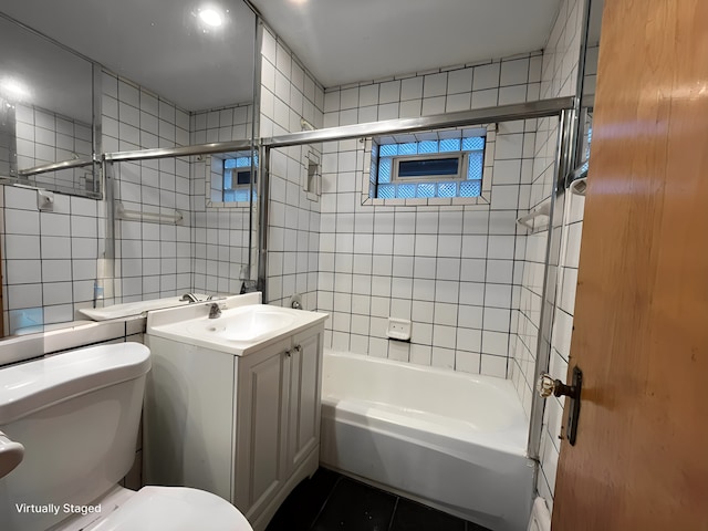 full bathroom featuring toilet, vanity, bathtub / shower combination, and tile walls