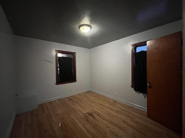 spare room featuring baseboards and wood finished floors