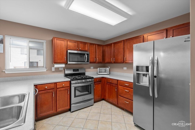 kitchen with light tile patterned floors, appliances with stainless steel finishes, light countertops, brown cabinets, and a sink