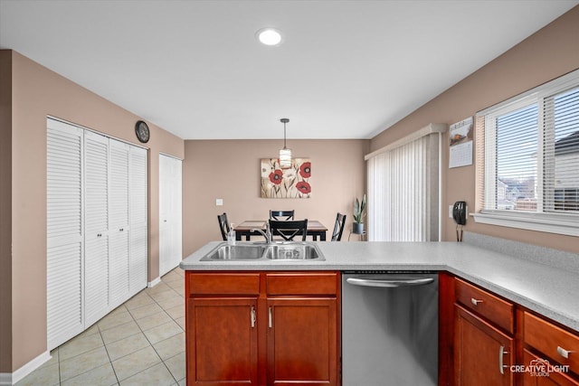 kitchen featuring light tile patterned floors, stainless steel dishwasher, a sink, light countertops, and hanging light fixtures